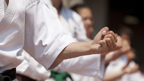 Nahaufnahme von Karateka in weißer Kleidung, die ihre Fäuste zur Vorbereitung auf einen Technik- oder Kiyya-Wurf anheben.